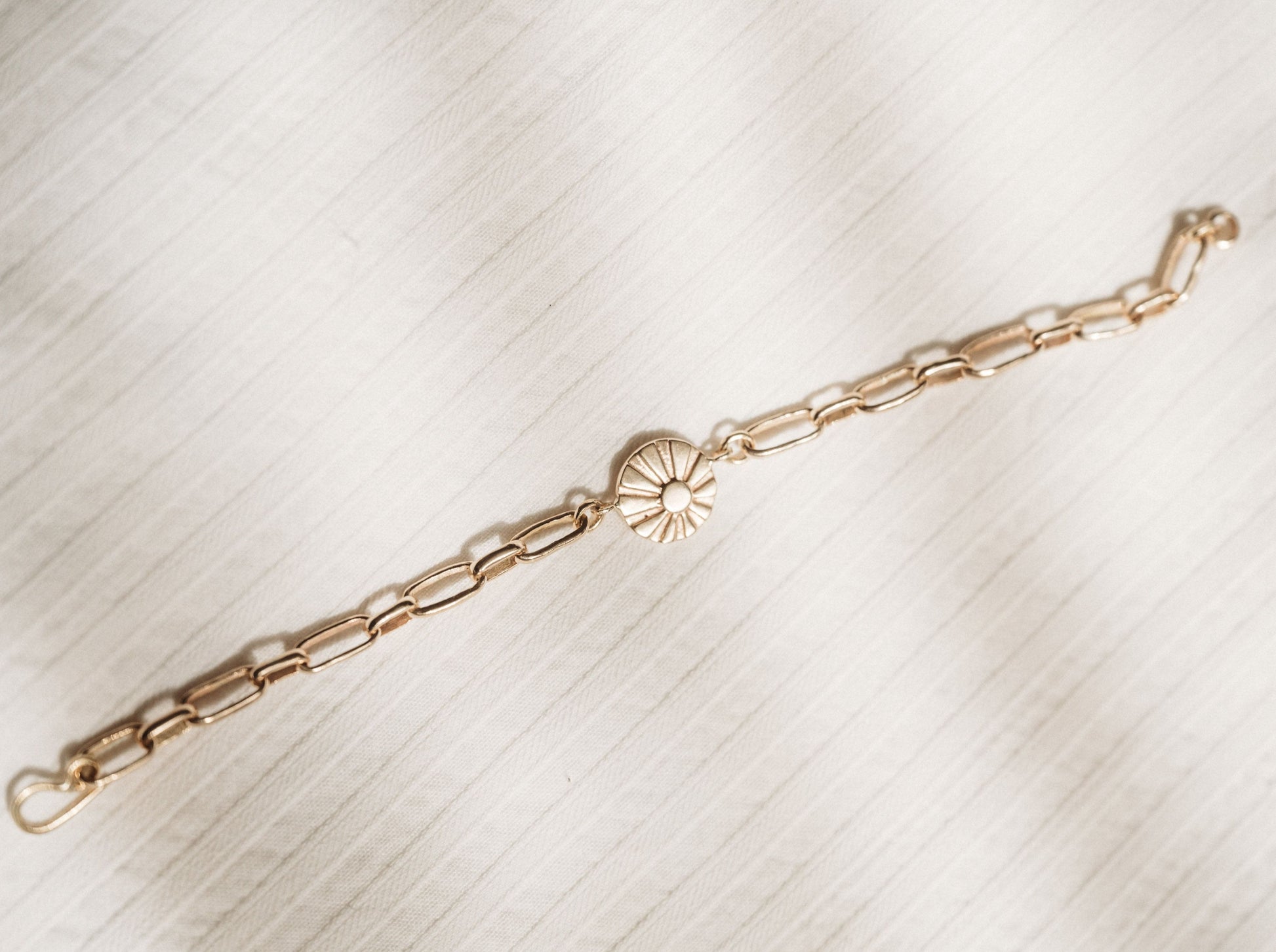 Heavy gold link chain bracelet with sun charm as focal point