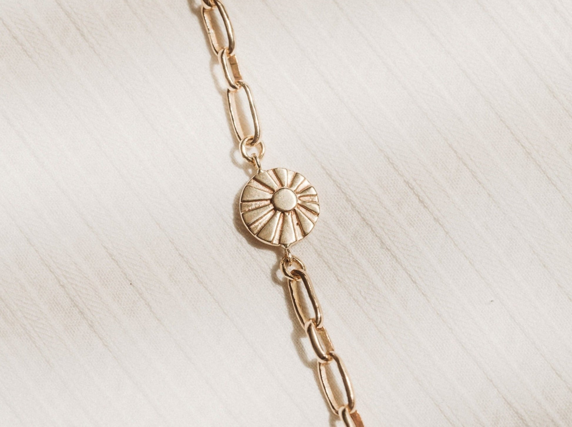 Heavy gold link chain bracelet with sun charm as focal point